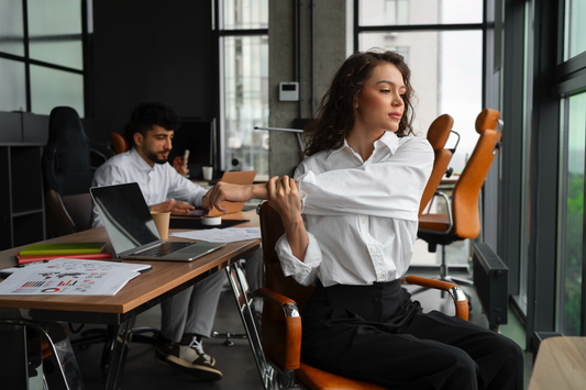 Woman sitting at an office desk rubbing her neck due to poor posture and long hours of sitting